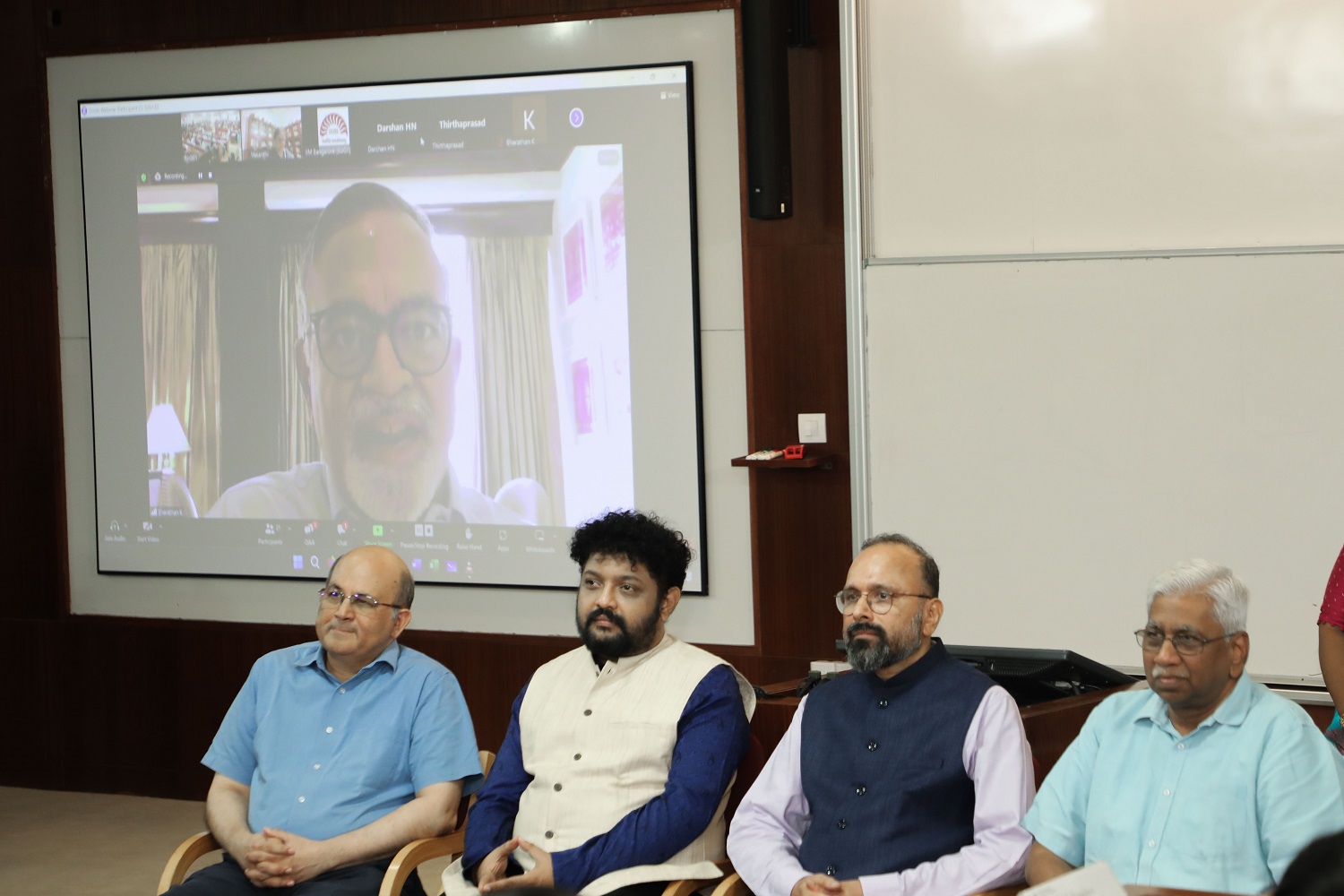 On screen is Professor Kandaswamy Bharathan, Creative Producer of Kavithalayaa Films, at the launch of the IIMB Song. (L-R) IIMB Director Professor Rishikesha T Krishnan, Music Director Navneeth Sundar, IIMB Alumnus-Author-Entrepreneur and member of the winning team of lyricists Pashupati Davella, and Dean Administration Professor Rajendra K Bandi, during the launch.